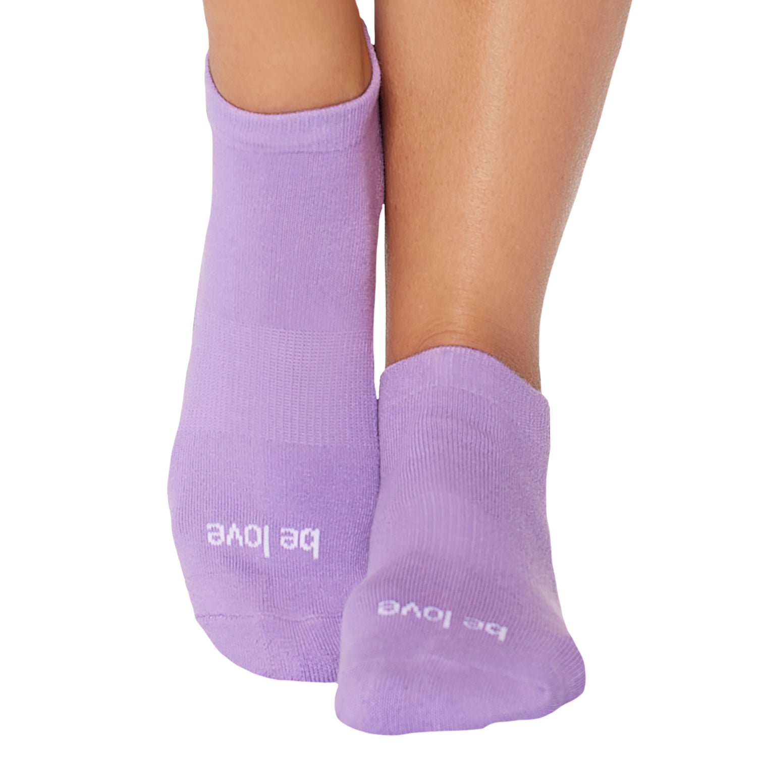 A pair of purple grip socks with the text 'be love' written on them, worn on someone's feet.
